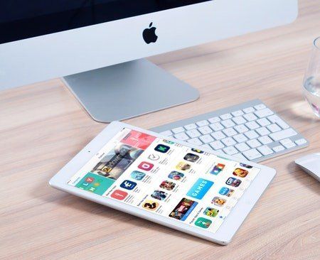 A tablet is sitting on a desk next to an apple computer